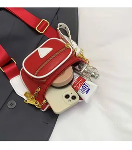 Rangement intérieur du sac ceinture en cuir rouge montrant téléphone et cosmétiques