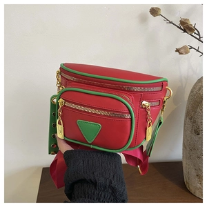 Détail du sac ceinture en cuir rouge avec liserés verts et finitions métalliques dorées