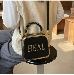Detail of black octagonal box bag with gold metal frame and 3D HEAL letter logo