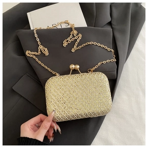 Primo piano di una pochette dorata di paillettes con catena sottile su uno sfondo di blazer