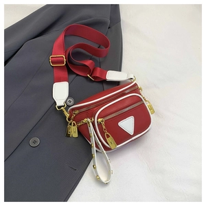 Détail du sac ceinture en cuir rouge avec bordure blanche et écusson triangulaire chic