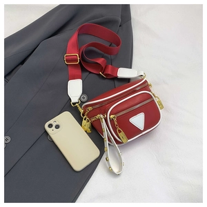Détail du sac banane en cuir rouge avec bordures blanches et fermetures éclair dorées