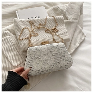 Close-up of white lace evening bag with rhinestones, gold frame and delicate chain