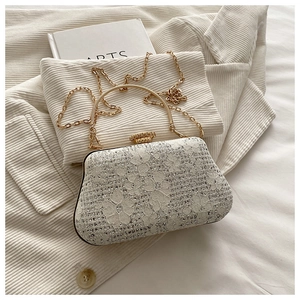 Detailed close-up of white floral lace and sparkling rhinestones on an elegant evening clutch