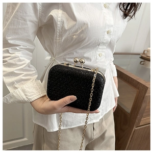 Dettaglio dell'elegante borsa da sera nera glitterata con catena dorata su camicia