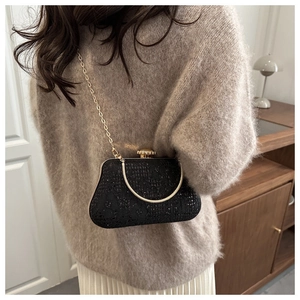 Close-up of black lace glitter evening bag with gold ring handle and chain strap