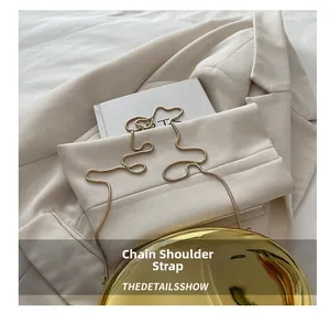 Detail shot of a round gold mirror acrylic clutch bag with a slim metal snake chain strap