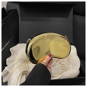 Close-up of golden mirror finish acrylic clutch with sleek chain in a luxury gift box