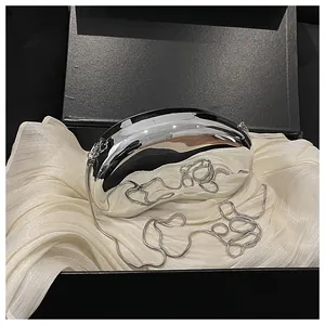 Close-up of pebble-shaped mirror silver evening clutch with elegant snake chain strap