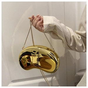 Detail of a shiny gold paisley acrylic clutch bag with a metal chain shoulder strap