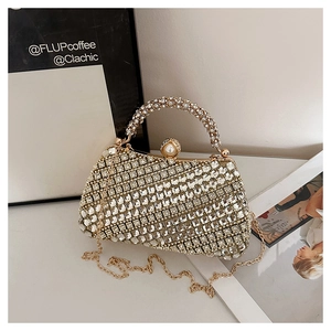 Détail du sac de soirée doré avec strass, fermoir en perle et poignée ronde métallique