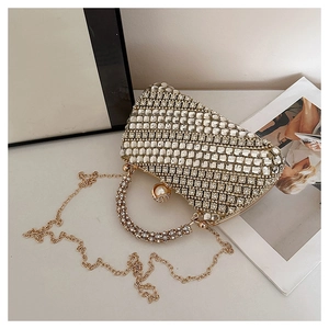 Détail de pochette de soirée avec strass, fermoir perle et bandoulière en chaîne dorée