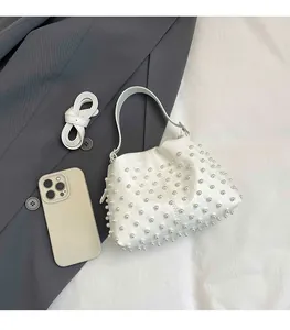 Vista dettagliata dall'alto di una borsa a secchiello bianca con perle e telefono per misura