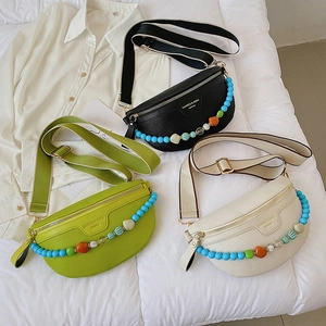 Three half-moon crossbody chest bags in black, green and beige with beaded chains