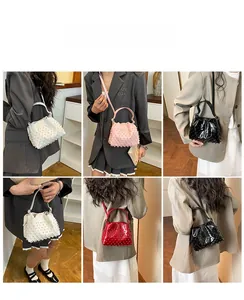Dettaglio della borsa a secchiello con perle e texture a pieghe in bianco rosa nero e rosso