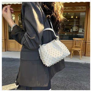 Scatto in strada di una borsa a secchiello bianco crema con eleganti decorazioni di perle