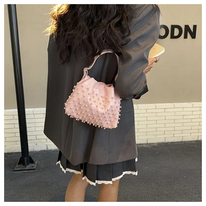 Dettaglio della borsa a secchiello rosa chiaro con perle indossata da una modella