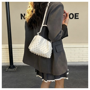 Dettaglio della borsa a secchiello plissettata bianca con perle indossata da modella