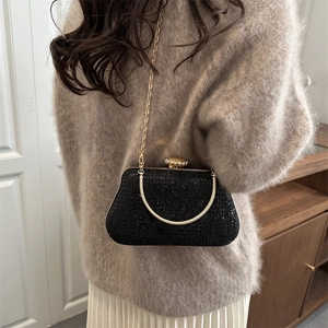 Elegant black evening clutch with gold chain strap and crystal clasp shown in lifestyle view