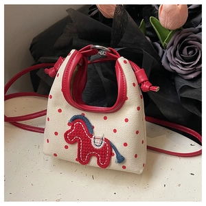 Detailed view of red polka dot canvas bag featuring horse embroidery and red handles