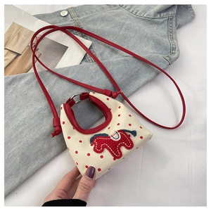 Detail of cartoon pony patch on cream canvas polka dot mini bag with red handles