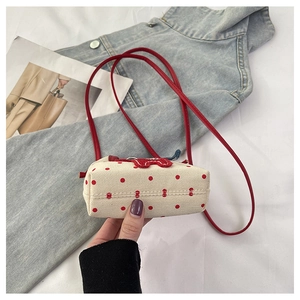 Detail of canvas mini crossbody bag with red polka dots and heart charm accessory