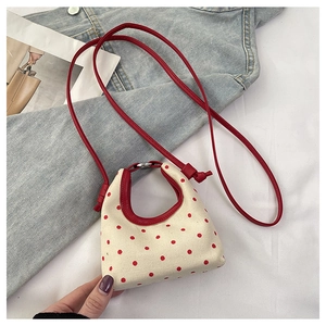 Detailed macro view of mini canvas crossbody bag featuring red polka dots and faux leather strap