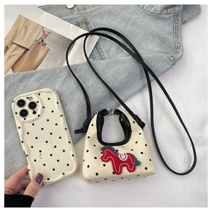 Detail of canvas polka dot mini bag featuring a red pony embroidery and shoulder strap