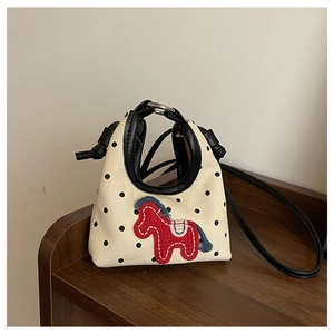 Detail of canvas mini bag featuring black polka dots and a red pony embroidery patch