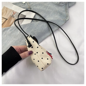 Detail view of mini polka dot canvas crossbody bag with delicate shoulder strap and embroidery