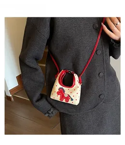 Detailed view of mini white canvas polka dot crossbody bag with red pony embroidery