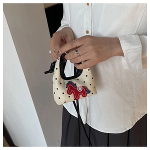 Detail of mini polka dot canvas bag with red pony embroidery held by model