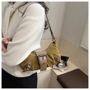 Détail de la texture toile olive et de la sangle en cuir brun sur le sac rétro porté épaule