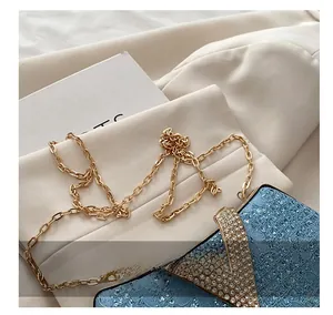 Detail of light blue lace clutch with gold chain and V-shaped rhinestone buckle closure