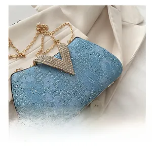 Detail of light blue lace evening bag with gold V-shaped rhinestone clasp on a blazer