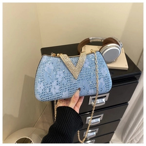 Detail of light blue lace evening bag with rhinestone V-clasp and gold chain strap