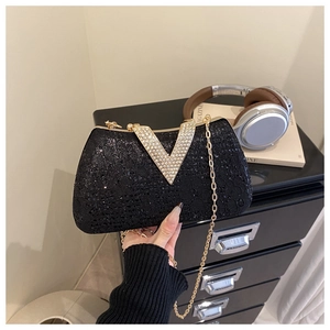 Detail of black rhinestone clutch bag with gold chain strap and sparkling V buckle