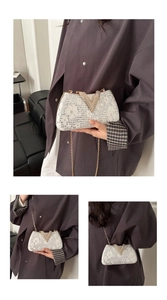 Detail of white lace evening clutch with V-shaped rhinestone buckle and gold chain strap