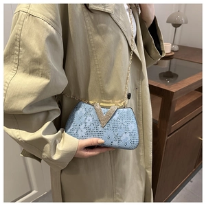 Detail of light blue lace evening bag featuring a rhinestone V-clasp and gold chain strap