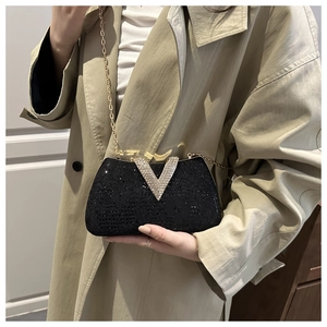 Detail of black lace evening bag with rhinestone V-clasp and elegant gold chain strap