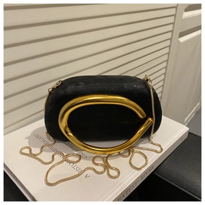 Detail of elegant black evening bag with oversized golden C-handle and snake chain strap