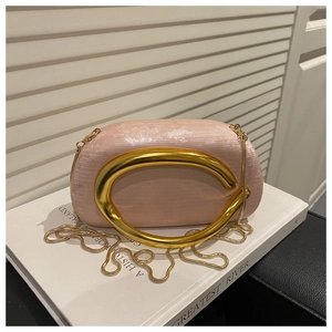 Detail of pink satin evening clutch with metallic gold circular handle and snake chain strap