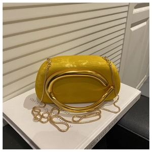 Detail of yellow evening clutch featuring C-shaped gold handle and luxury satin texture