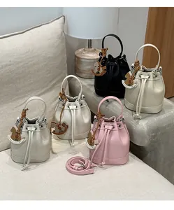 Detail of mini drawstring bucket bags with leather texture and horse charms in soft home setting