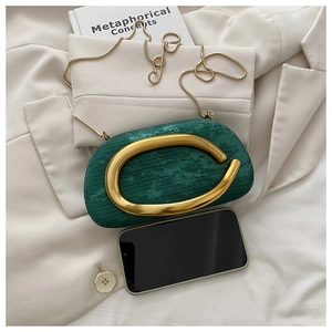 Detailed view of emerald green textured clutch bag with gold hardware and snake chain