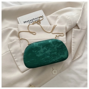 Detail of dark green marble textured clutch bag with a slim golden metal chain strap