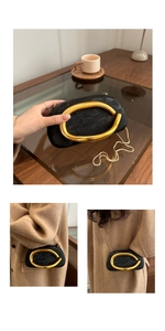 Detail of black evening clutch with large gold oval handle and thin metal chain strap