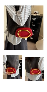 Detail of red velvet clutch with gold metal clasp and thin chain shoulder strap