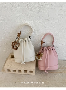 Close-up of bucket bags with drawstring closure and horse pendant charms on textured background