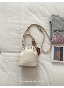 Top view of beige bucket bag with drawstring and pebbled leather texture on white fabric